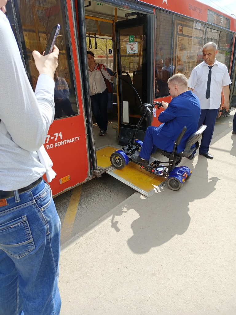 Въезд человека, передвигающегося на коляске, в автобус по автобусному пандусу.