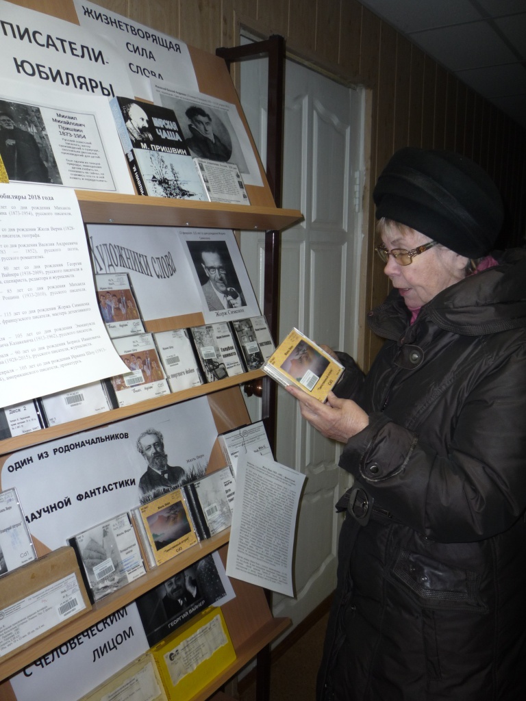 Читательница Казанского  филиала знакомится с книжной выставкой "Писатели-юбиляры"